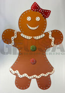 A cheerful brown gingerbread girl wall decoration with red polka-dot bow white icing trim by impression gingerbread