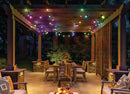 Colorful smart rgbw outdoor string lights by gilbert engineering usa hang from wooden pergola lighting outdoor dining area warmly